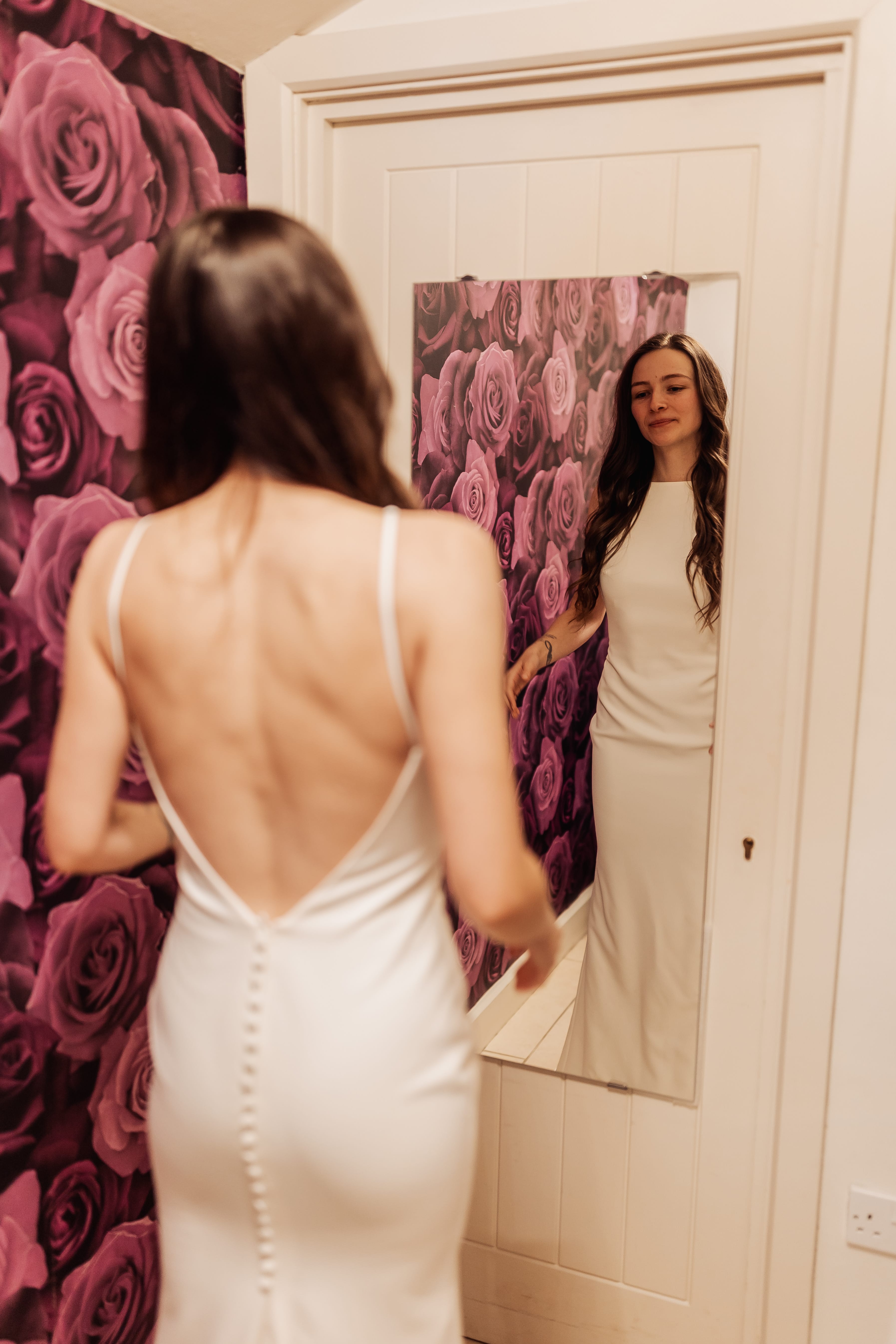Jade in her Wedding Dress displaying the back whilst looking into a mirror